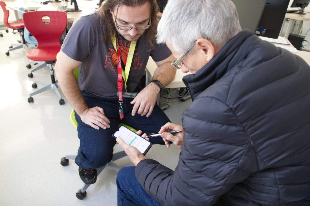 Fotografija svetovalca in odraslega med delom s pametnim telefonom.