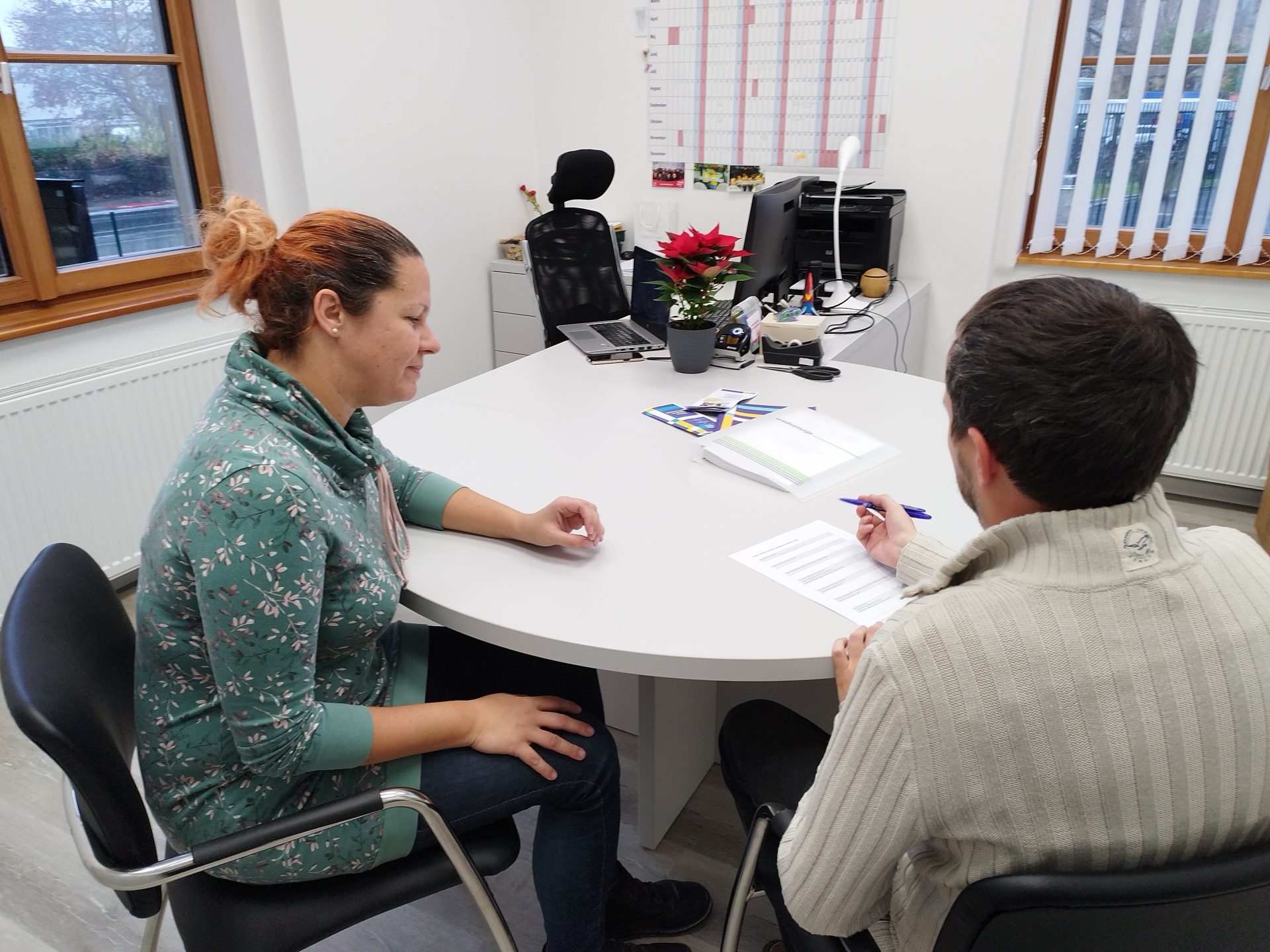 Fotografija svetovalke in odraslega v pogovoru.