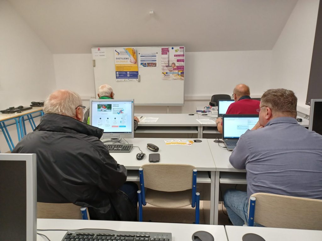 Skupina odraslih med učenjem v računalniški uilnici.